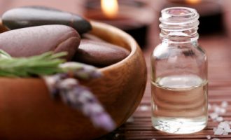 bottle of essential oil, massage stones,candles,lavander and bath-salt in a tight composition